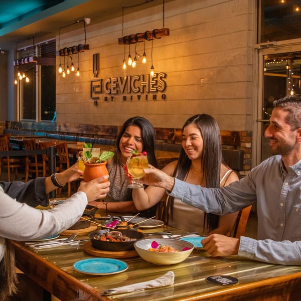 Four happy diners toasting drinks and enjoying Peruvian food at Ceviches by Divino restaurant.